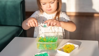 Little girl playing with sensory water beads, hydrogel balls.